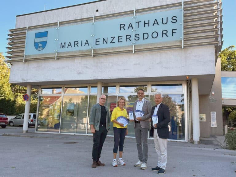 Vier Personen stehen mit Gehzeit.karten vor dem Rathaus