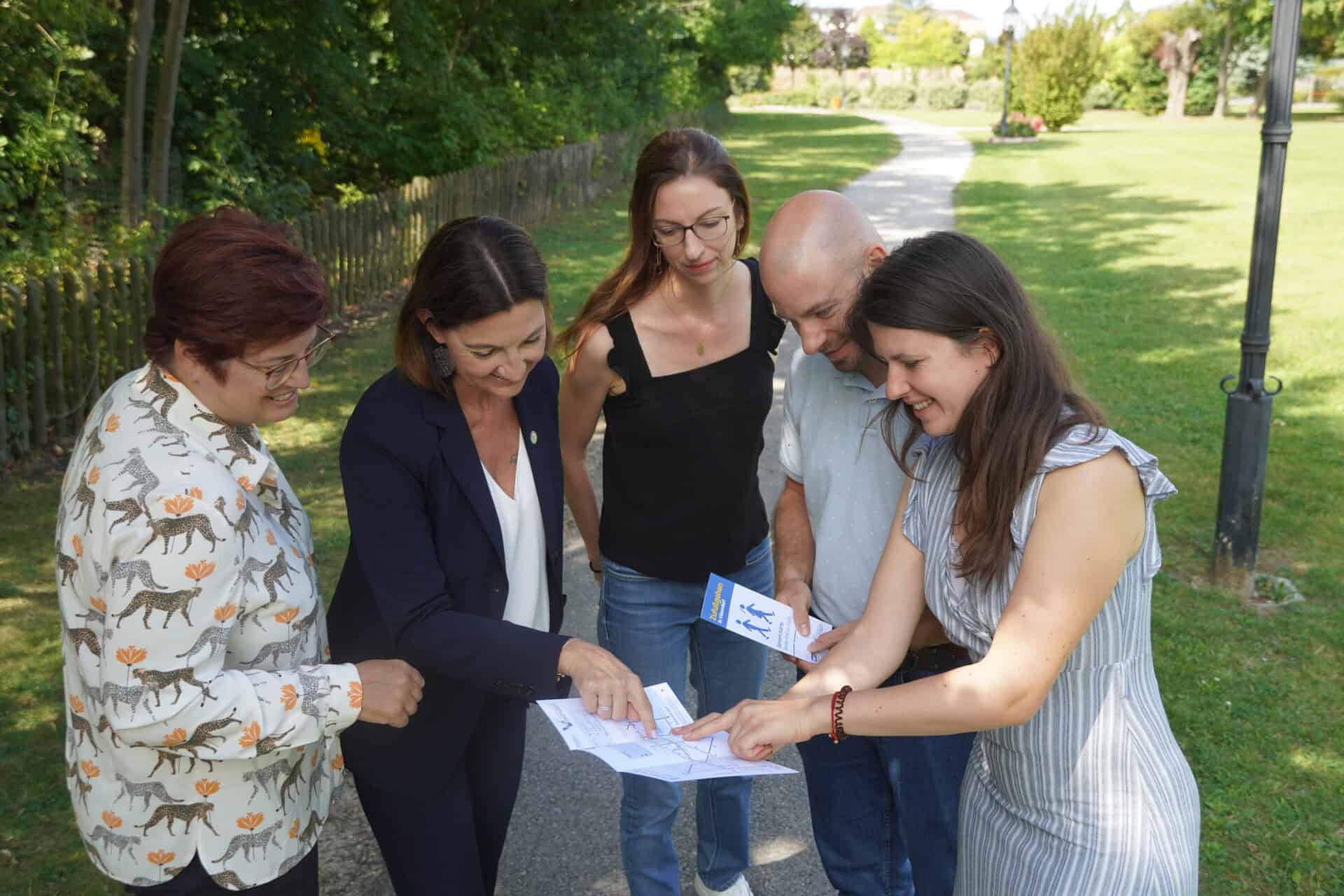Beteiligte an der Gehzeit.Karte Vösendorf stehen um einen Folder herum und schauen sich die Karte gemeinsam an.