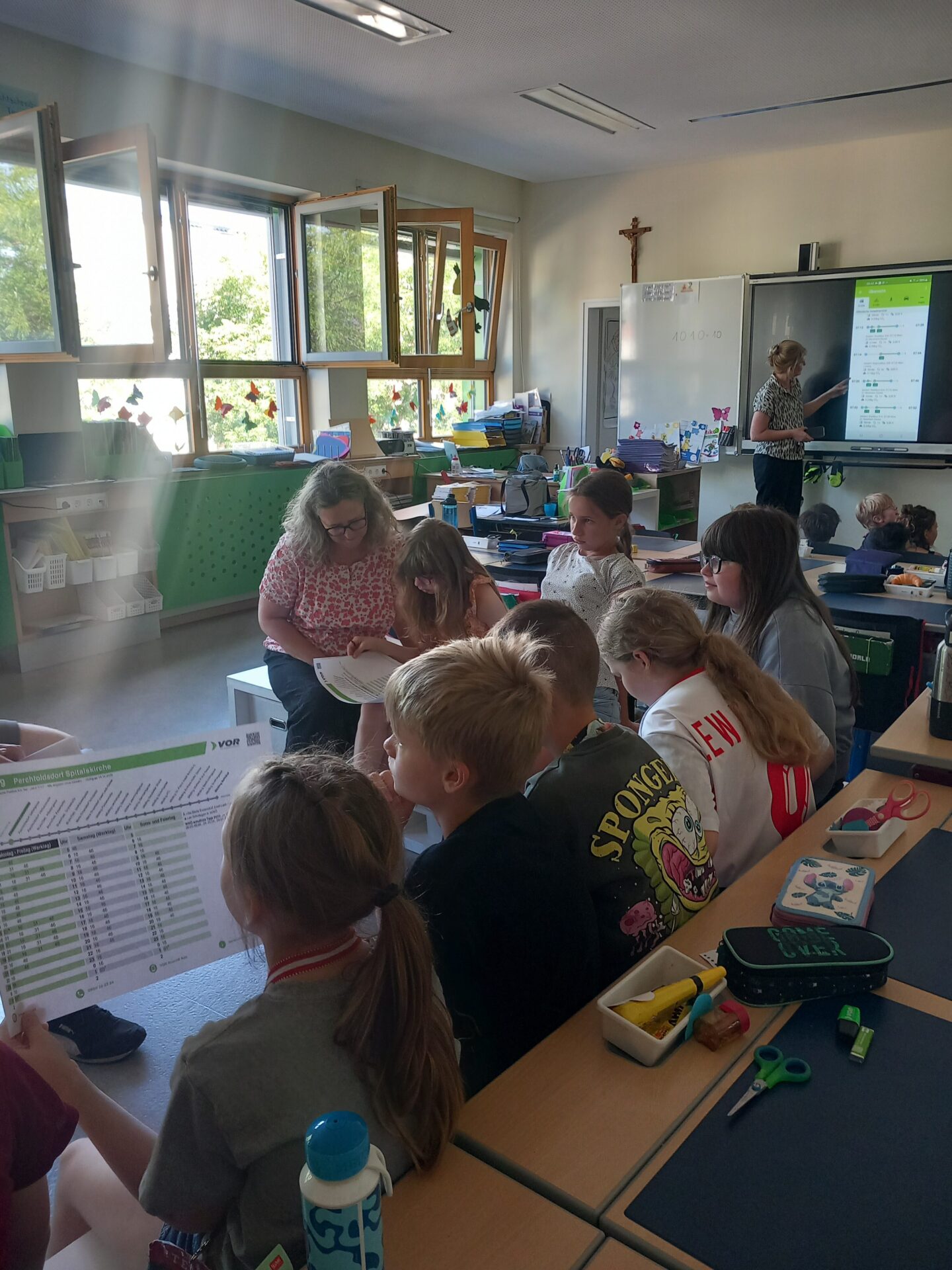 Kinder lesen Haltestellenaushang und lernen über Routenplaner-App