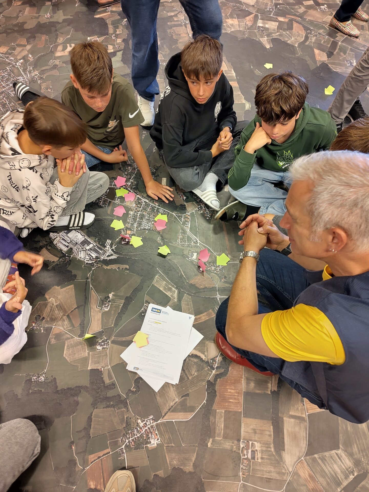 Kinder besprechen Problemstellen in Weinburg anhnad eines Luftbildes mit Bürgermeister Michael Strasser